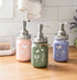 Farmhouse Whimsy butterfly mason jar soap dispenser with peach liquid soap and a decorative pump, rustic farmhouse style.