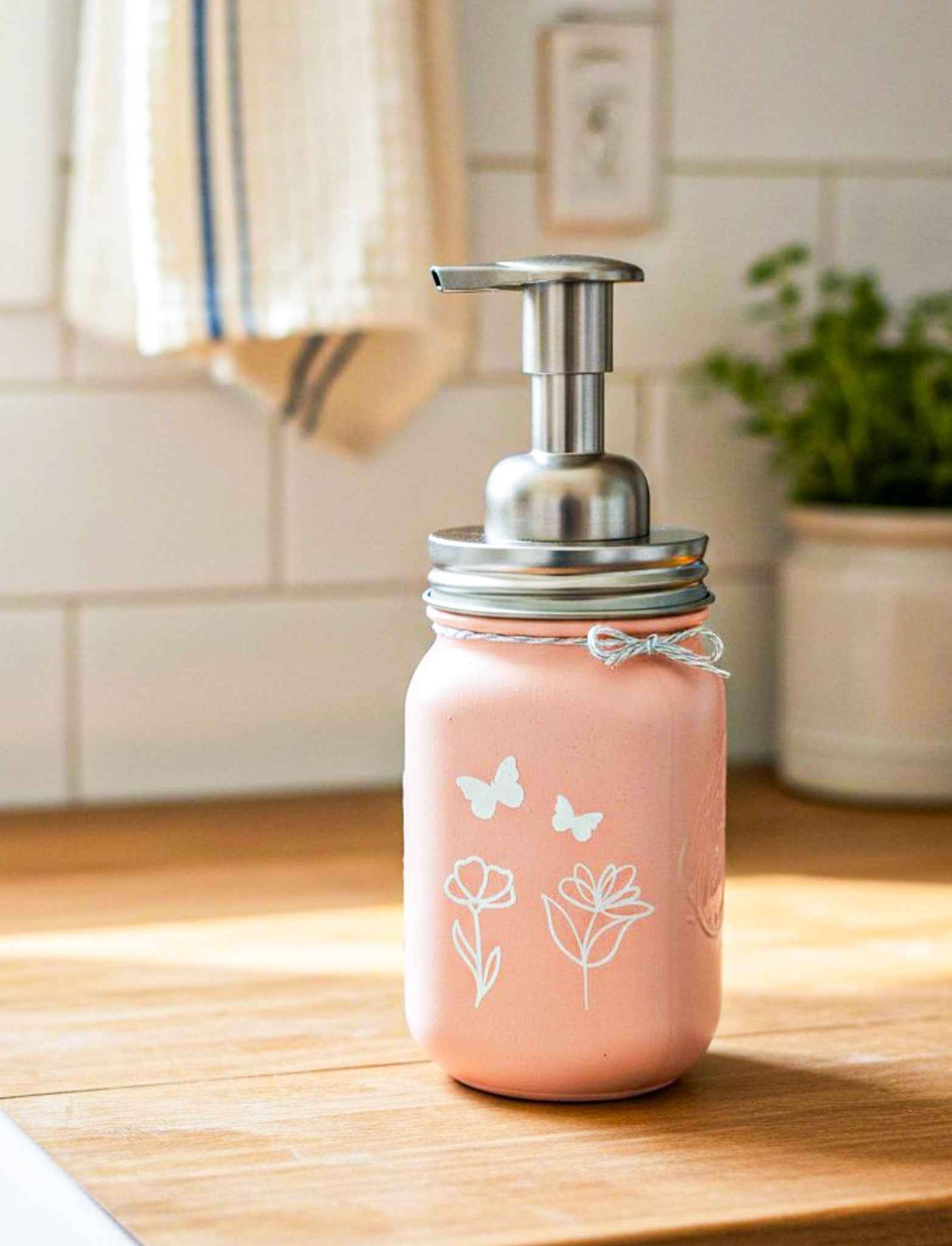 Farmhouse Whimsy butterfly mason jar soap dispenser with peach liquid soap and a butterfly design on a rustic soap jar.