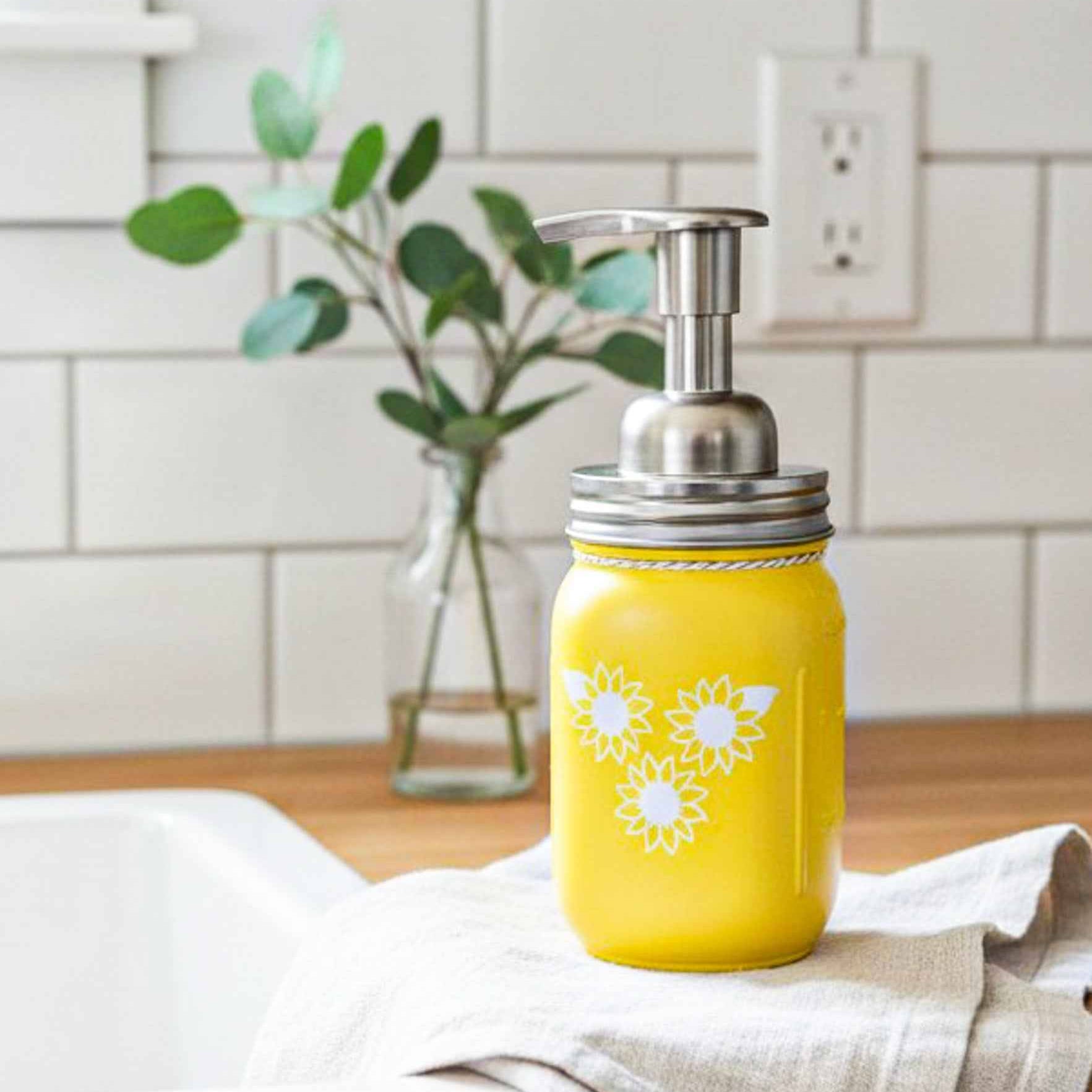 Farmhouse Whimsy sunflower mason jar soap dispenser with a rustic design and sunflower artwork on a white background.