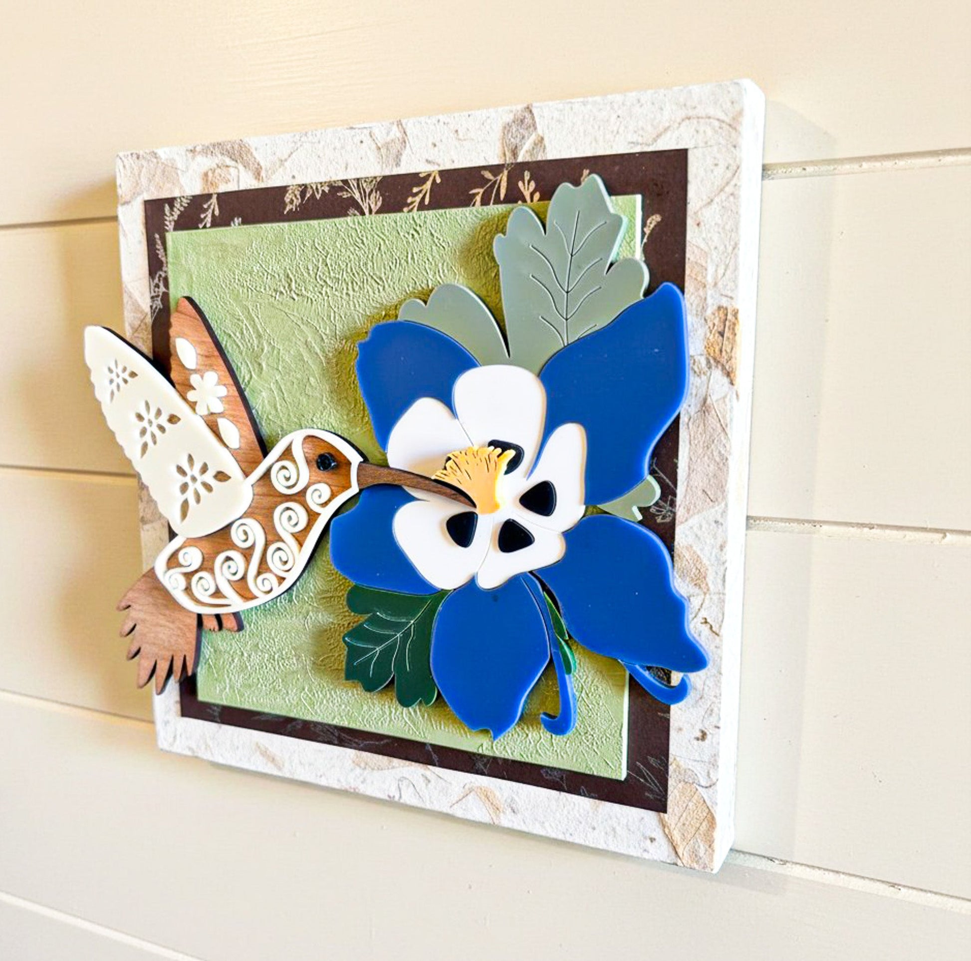 Hummingbird and columbine flower wall art by Farmhouse Whimsy showcasing colorful nature scene with vibrant blooms and bird.