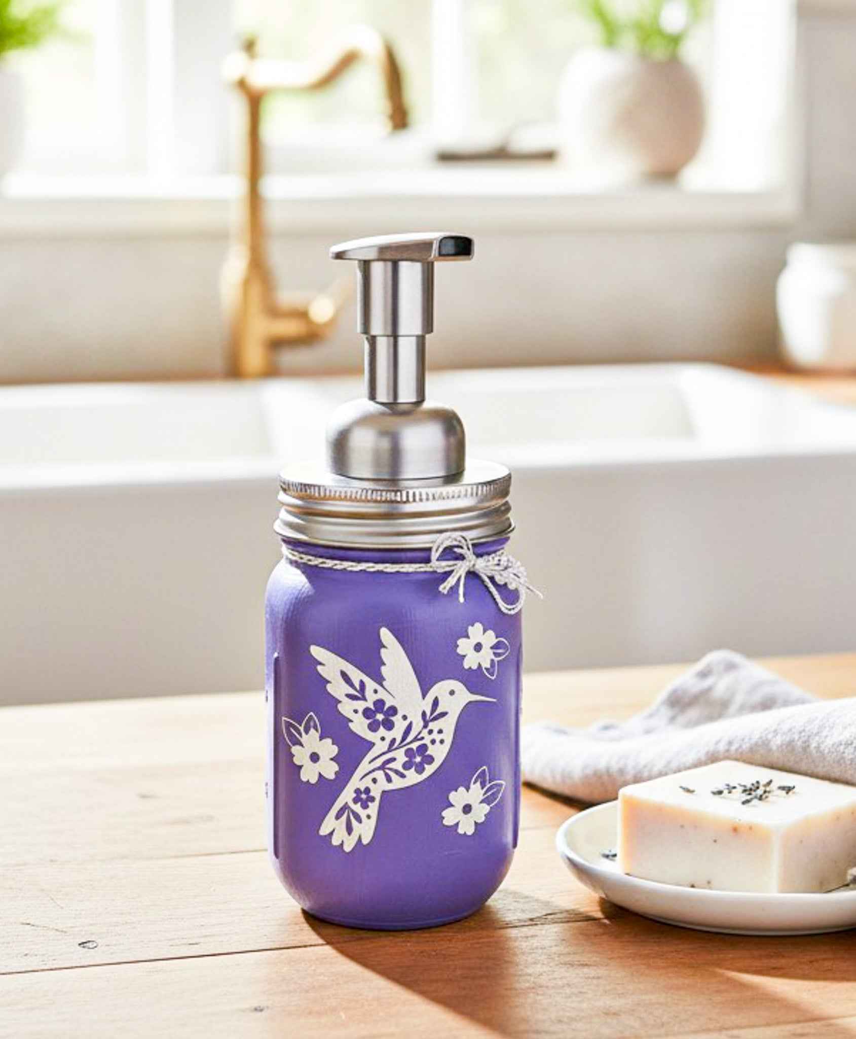Purple hummingbird mason jar soap dispenser with a thistle design from Farmhouse Whimsy, featuring a vintage-style glass jar and pump.