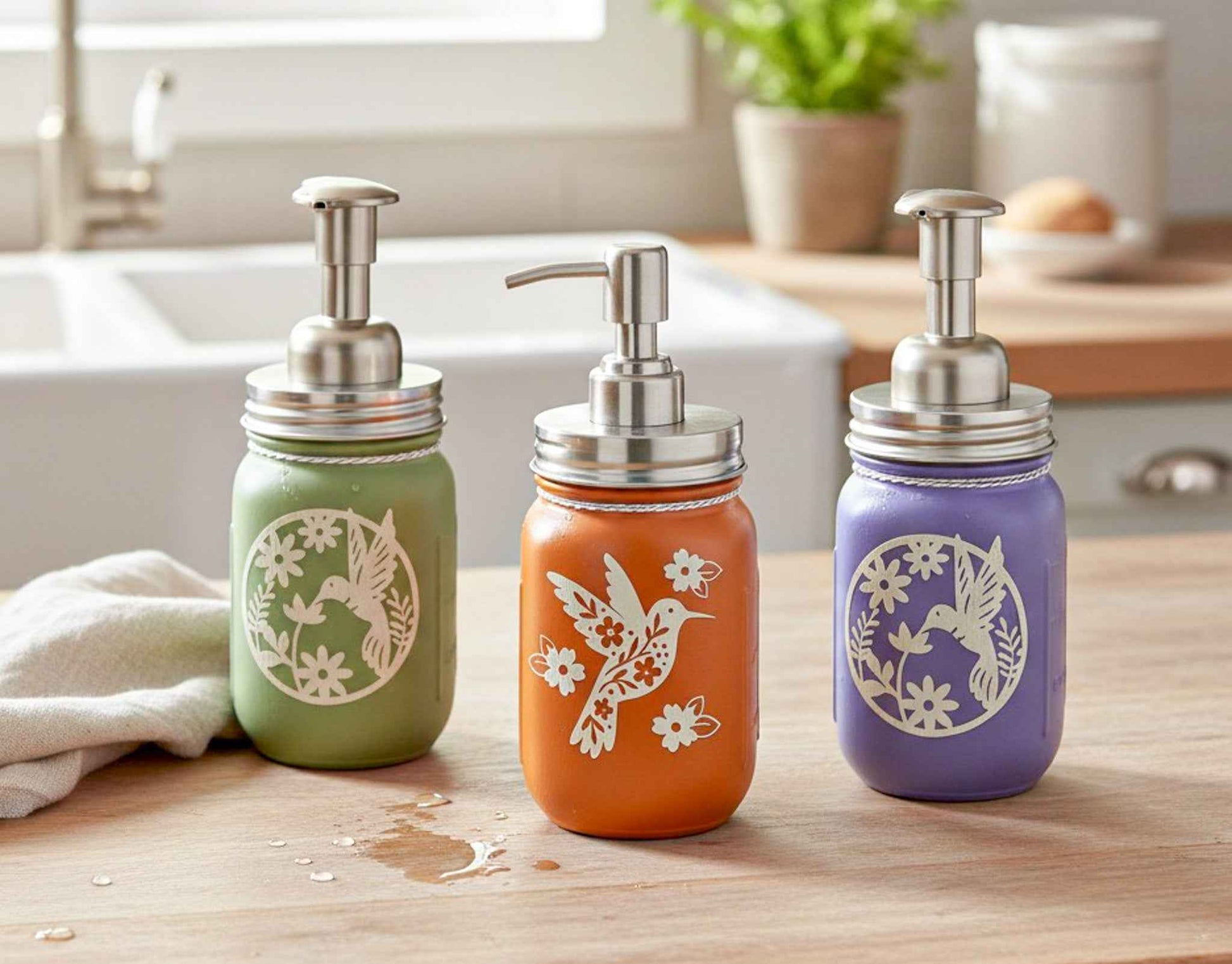 Farmhouse Whimsy hummingbird mason jar soap dispenser trio with decorative glass jars and pump tops for kitchen or bathroom use.