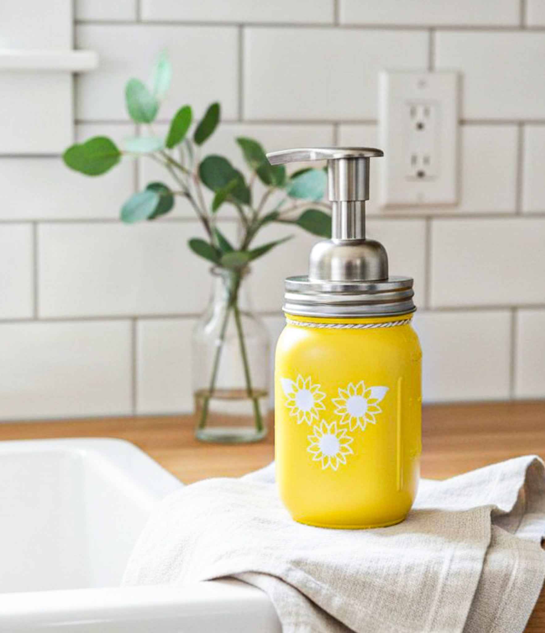 Farmhouse Whimsy sunflower mason jar soap dispenser with a rustic design and sunflower artwork on a white background.